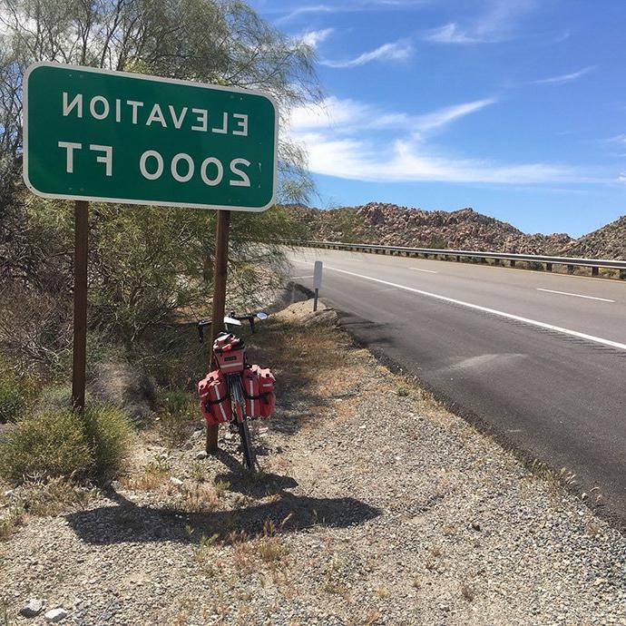 Road and bicycle with road sign that states "elevation 2000 ft"